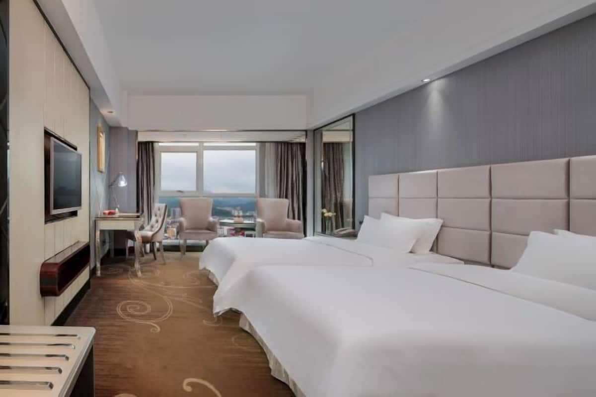 Une chambre d’hôtel avec deux lits, une télévision, un bureau et une chaise.