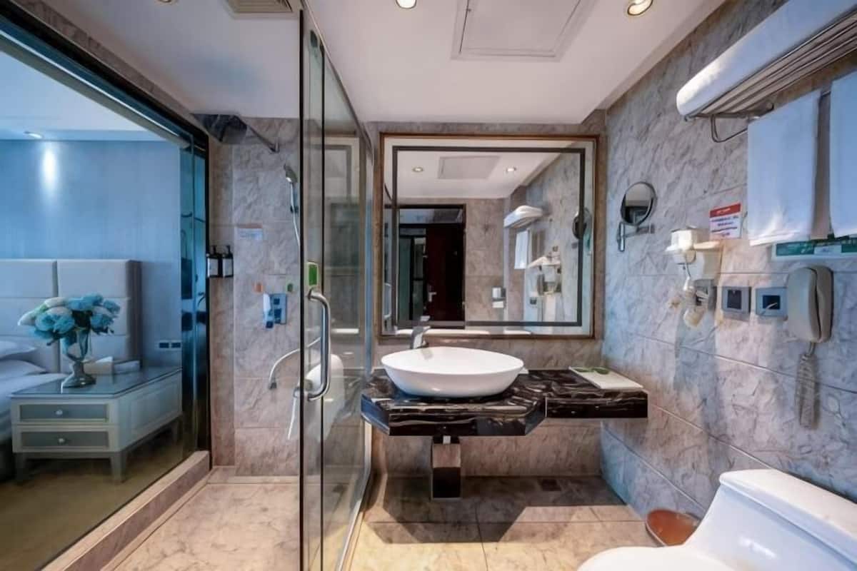 Une salle de bain moderne avec une douche à l’italienne en verre, un lavabo en marbre et un grand miroir.