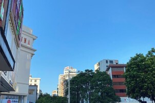 Un paisaje urbano con edificios, incluyendo un edificio blanco destacado con 'INA' y un cielo azul despejado.