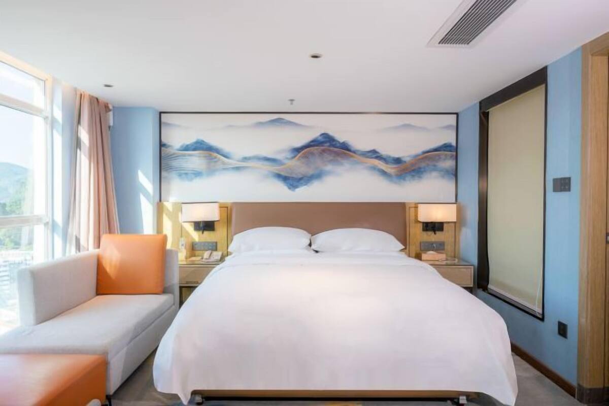 Une chambre d’hôtel avec un lit, un canapé, un tableau au mur et une fenêtre.