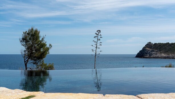 A pool with a clear view of the sea and a rocky outcrop in the background. - Sea front! Wonderfull villa with sea views from every room. (Capdepera)