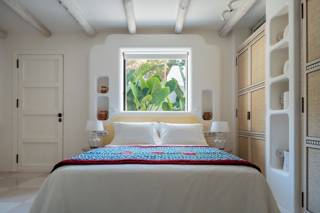 Une chambre à coucher avec un lit, une fenêtre donnant sur un espace verdoyant, une porte et une armoire.