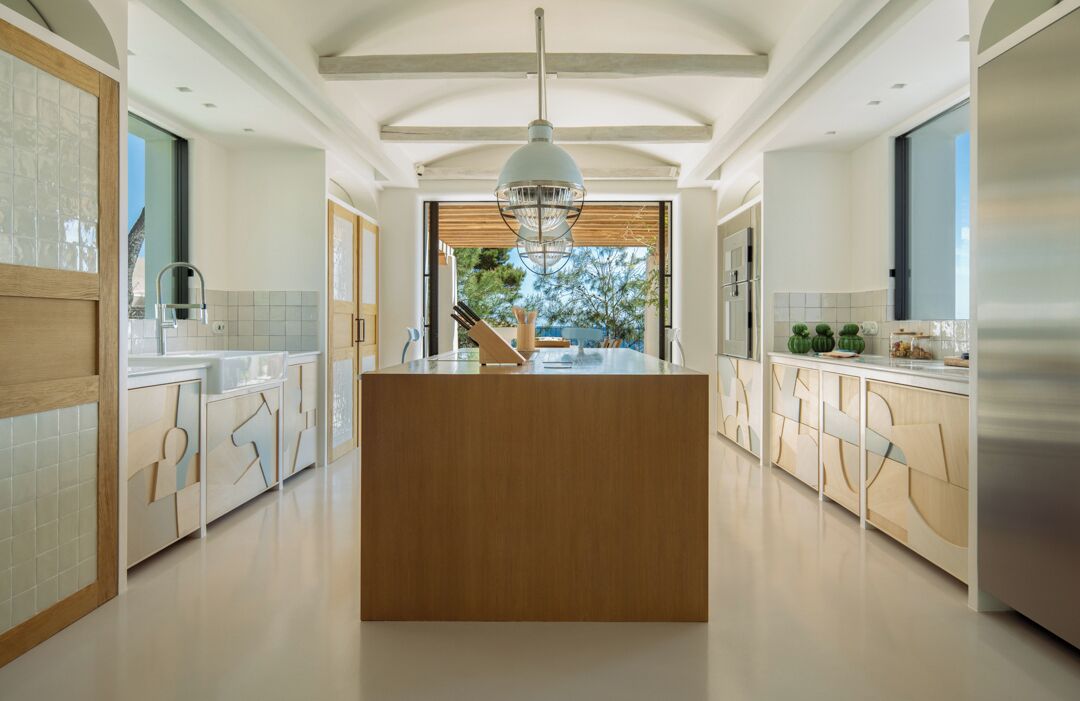 A modern kitchen with a central island, wooden cabinets, and a large window providing a view of the outdoors.