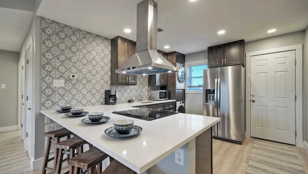 A modern kitchen with a central island, stainless steel appliances, and patterned backsplash. - Sleeps 22 3 Condos in Beachfront Complex w/ Pool, Pickleball Island Retreat (Port Aransas)