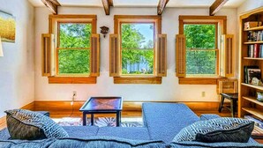 A room with a wooden ceiling, a sofa, a small table, and a bookshelf. - Lakefront Log Cabin at Lake Anna, Dock, Deck (Bumpass)