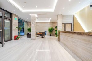 Rebuda d'hotel moderna amb taulell de recepció, zona de seients i plantes en testos.