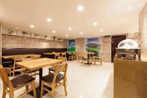 Interior de restaurant amb seients a caixa, taules i una estació de graella.