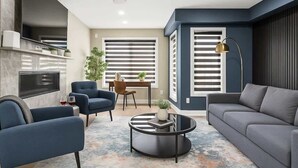 Una sala de estar moderna con sofá, sillones, una mesa de centro y televisor.