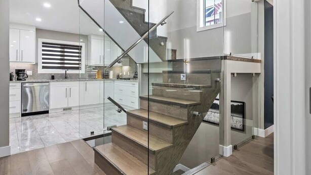 Una cocina moderna con una escalera de cristal que sube a un segundo piso.