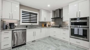 Una cocina moderna con armarios blancos, electrodomésticos de acero inoxidable y un salpicadero de azulejos.