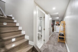Stylish hallway leads to a bathroom with a digital control panel and a wooden ladder.