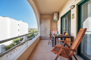 Enjoy the view from this balcony with a table, chairs, and a potted plant.