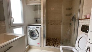 A compact bathroom with a washing machine, a shower enclosure, and a toilet. - The cytadin! Pied streetcar paris porte de choisi 11 minutes, Palais Royal musé 45 min (Vitry-sur-Seine)