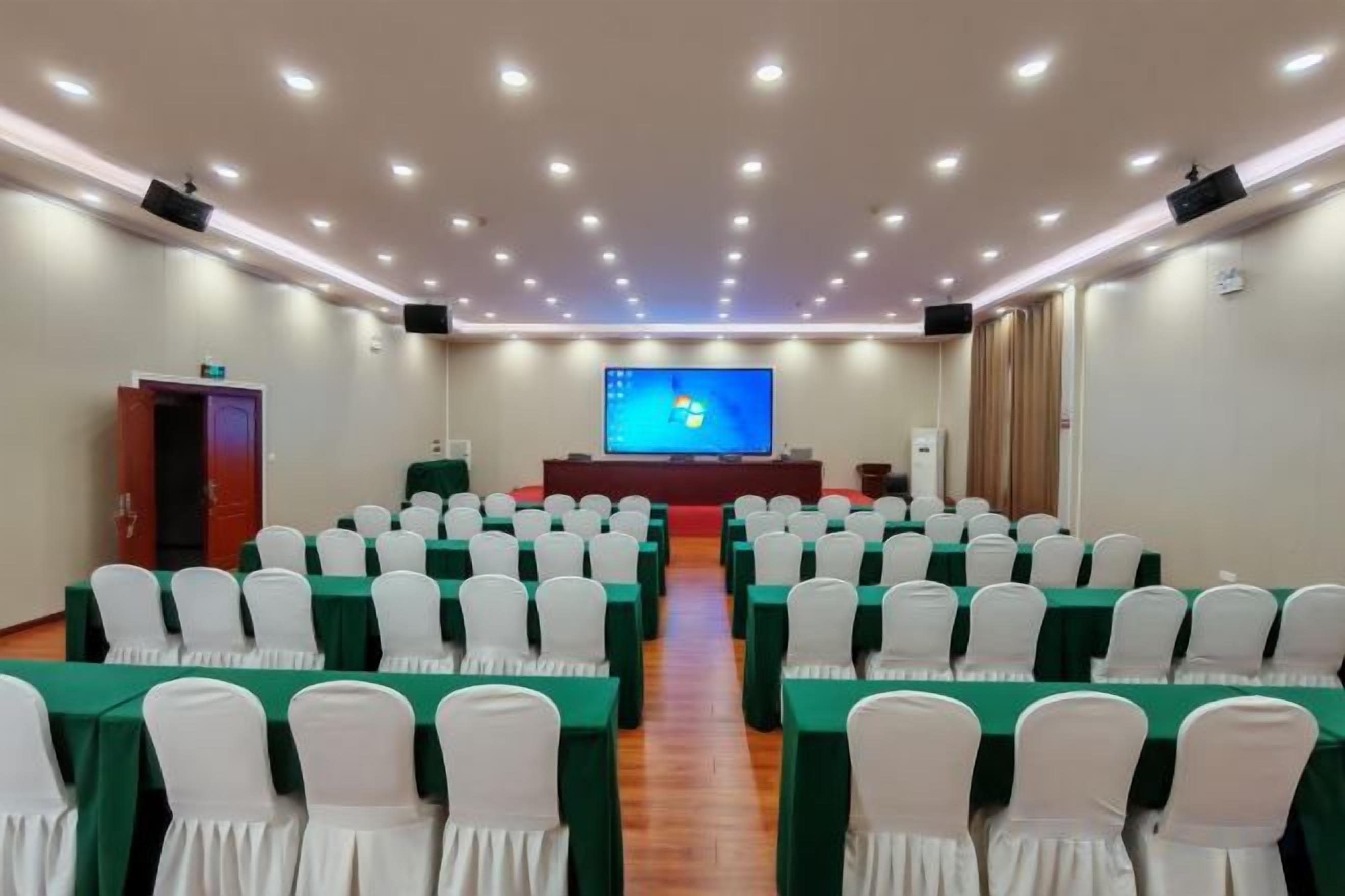 A conference room with rows of chairs, a stage with a screen, and a podium.