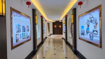 A hallway with posters on the walls, a tiled floor, and red lanterns.