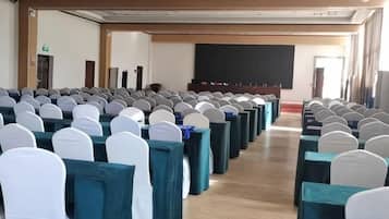 A conference room with rows of tables and chairs, a blackboard, and a projector screen.