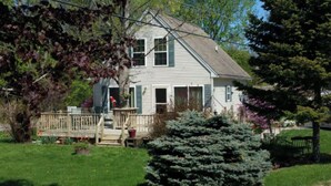 A two-story house with a front porch and a small deck. - Charming  3B/R  Cottage on Malletts Bay (Colchester)