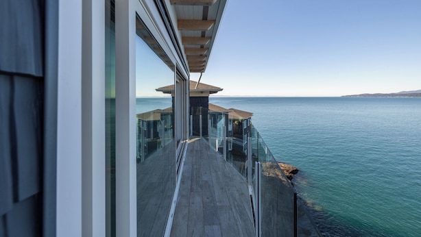 A modern balcony with glass railings overlooking a coastal sea. - Coastal View Sunset at SookePoint Cottages (Sooke)