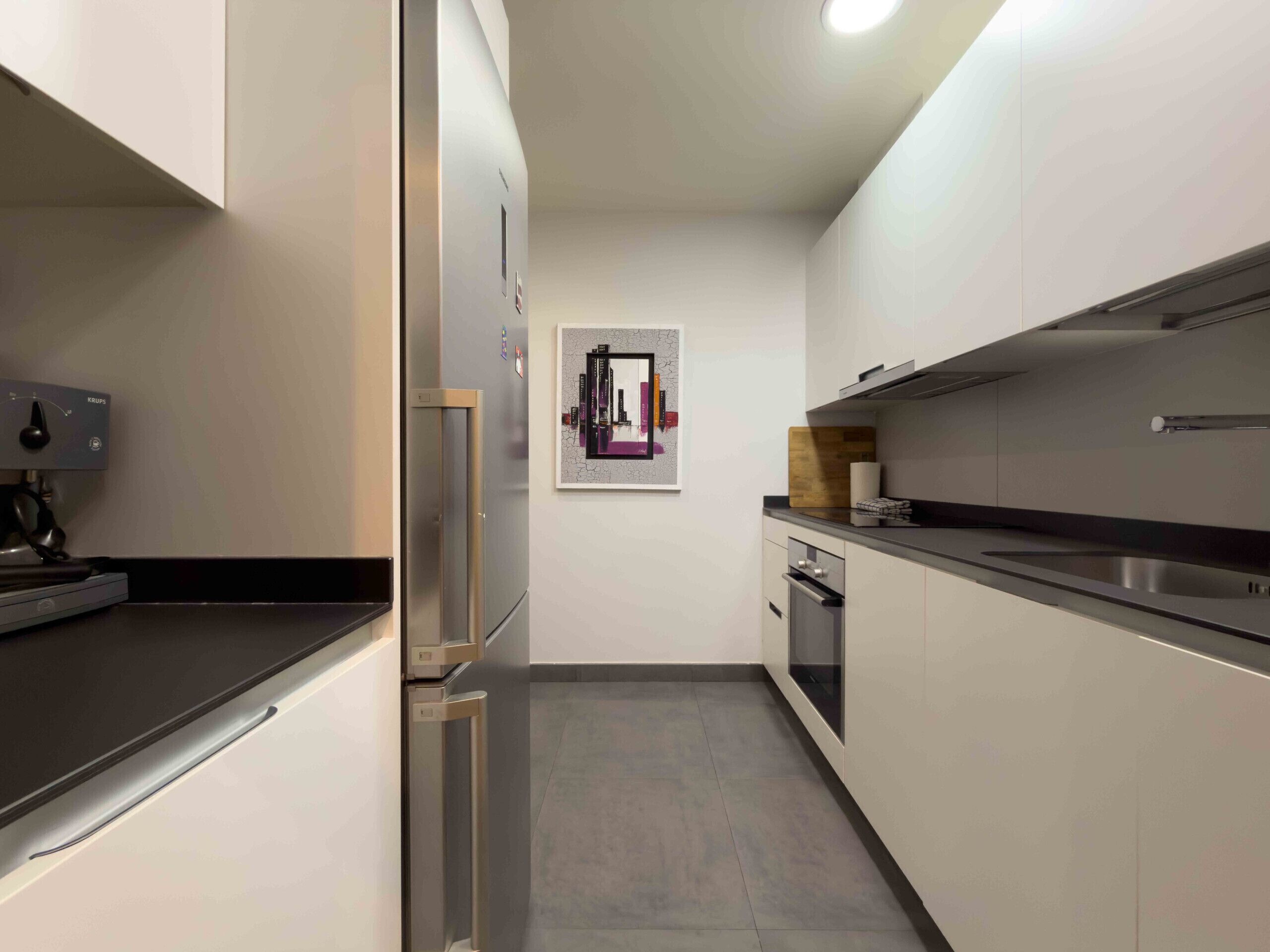 Una cocina moderna con horno empotrado, refrigerador y microondas.