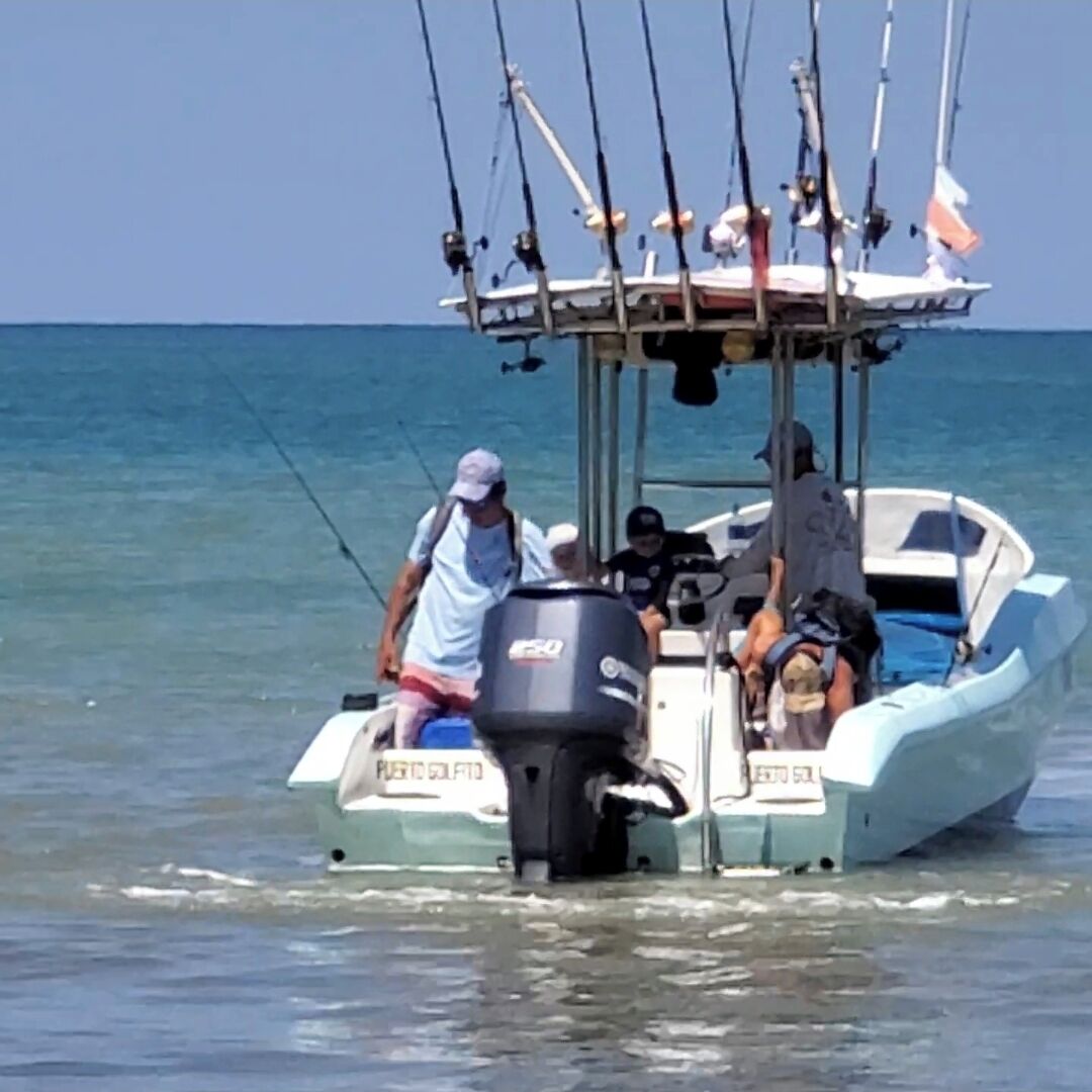 Een klein bootje met een motor en diverse hengels aan dek.