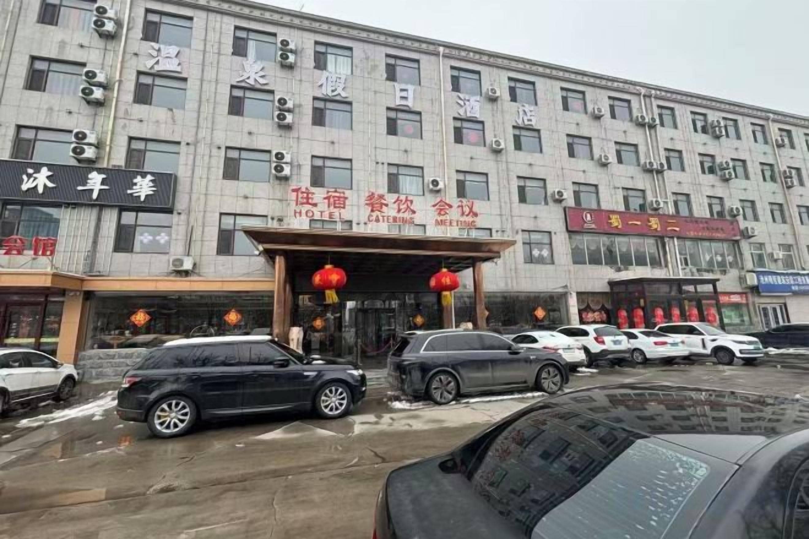 A hotel with a traditional facade, multiple floors, and a parking lot with several cars.