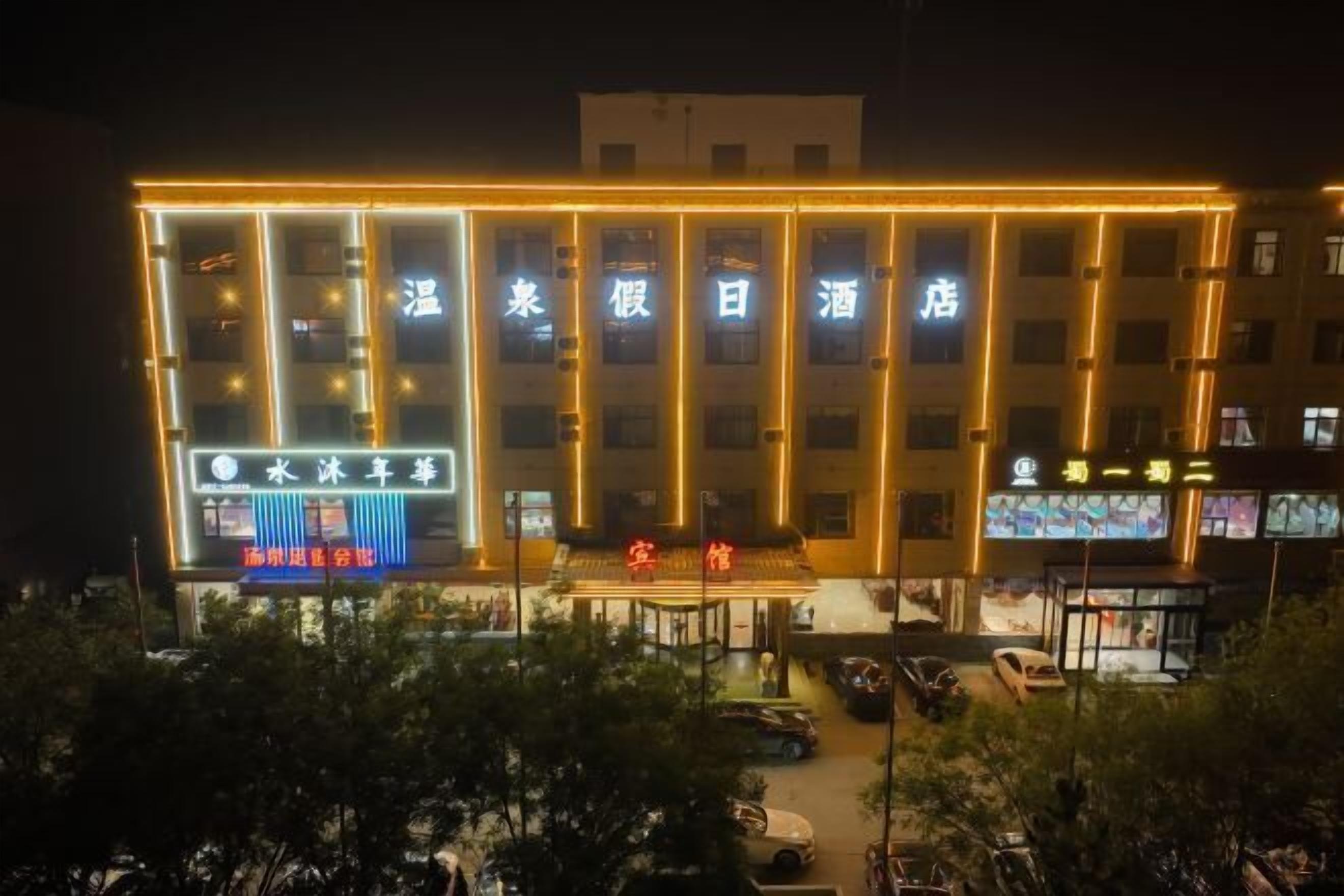 A hotel with multiple illuminated windows and a prominent sign in the center.