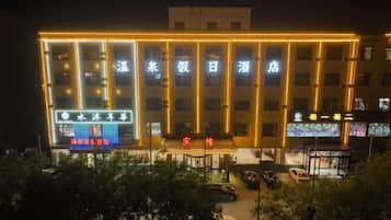 A hotel with multiple illuminated windows and a prominent sign in the center.