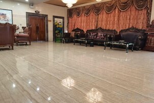 Un vestíbulo amplio con piso pulido, una recepción y un área de descanso con sofás y sillones.