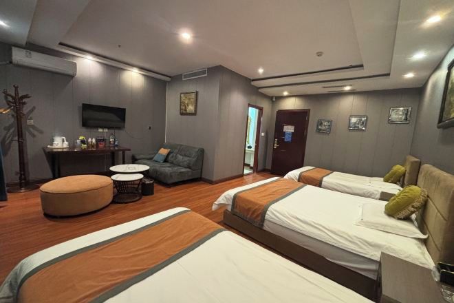 A hotel room with two beds, a sofa, a small table, and a TV.