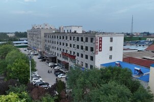 Un edificio de varios pisos con estacionamiento enfrente.
