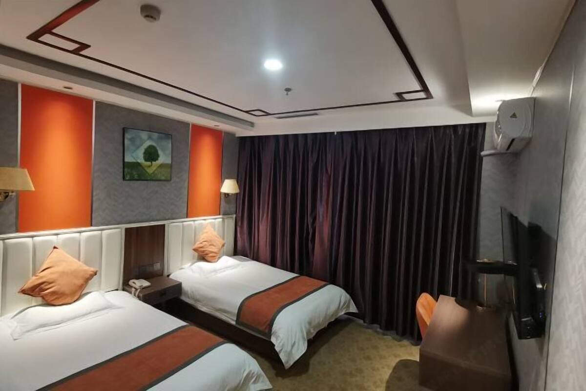 A hotel room with two beds, a TV, a desk, and a painting on the wall.