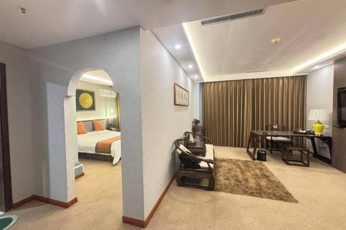 A hotel room with a bed, a desk, a chair, a television, and a curtain.
