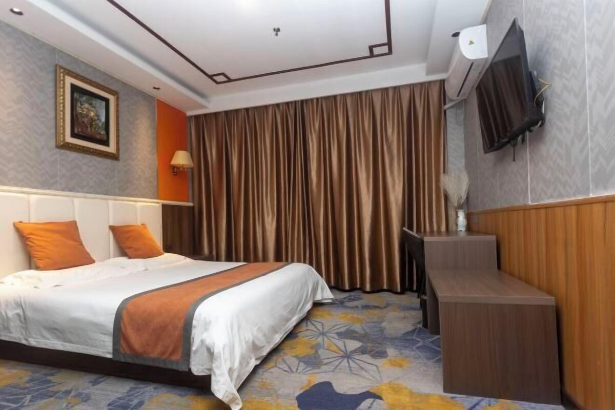 A hotel room with a bed, a desk, a TV, and a curtain.