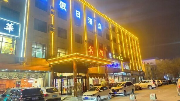 Ein Hotel mit einem markanten Eingang, mehreren Etagen und einer gut beleuchteten Fassade.