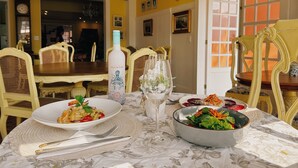 Una mesa de comedor con platos de comida, una copa de vino y una botella.