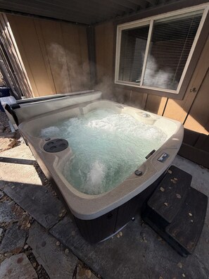 Een warmwaterbad met bedieningspaneel, omringd door stenen tegels en houten wanden.