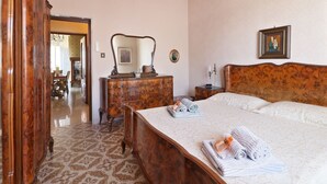 Hotellihuone, jossa on suuri sänky, puinen pääty, lipasto ja peili.