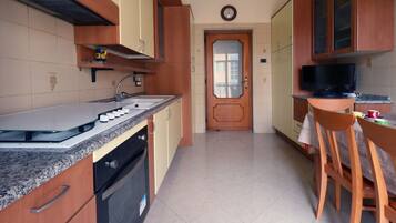 Una cucina con un piano di lavoro in granito, mobili in legno, forno integrato e zona pranzo con tavolo e sedie.