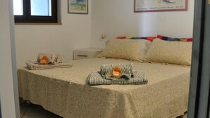 A neatly made bed with a floral bedspread, pillows, and a striped blanket. - BORGO SAN BASILIO: MOONLIGHT HOUSE - CON PISCINA E ANIMAZIONE DIURNA E SERALE (Pisticci)