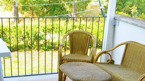 Un balcon doté de meubles en osier et offrant une vue sur un jardin.