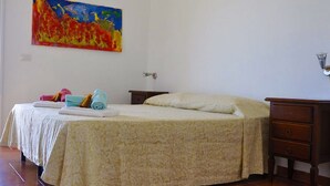 Habitación de hotel con cama, mesita de noche, cómoda y un cuadro en la pared.