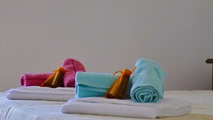 Un juego de toallas ordenado sobre una cama, con una pared lisa de fondo.