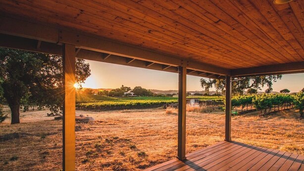 Un espace extérieur abrité, doté d’une terrasse en bois, entouré de vignobles et de champs à perte de vue.