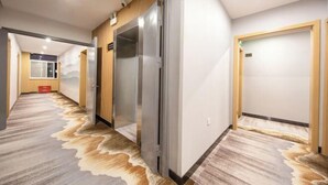 A hotel hallway with a patterned carpet, wooden doors, and a modern elevator. - City Ant Hotel (Nanjing Wutang Square Metro Station) (Nanjing)