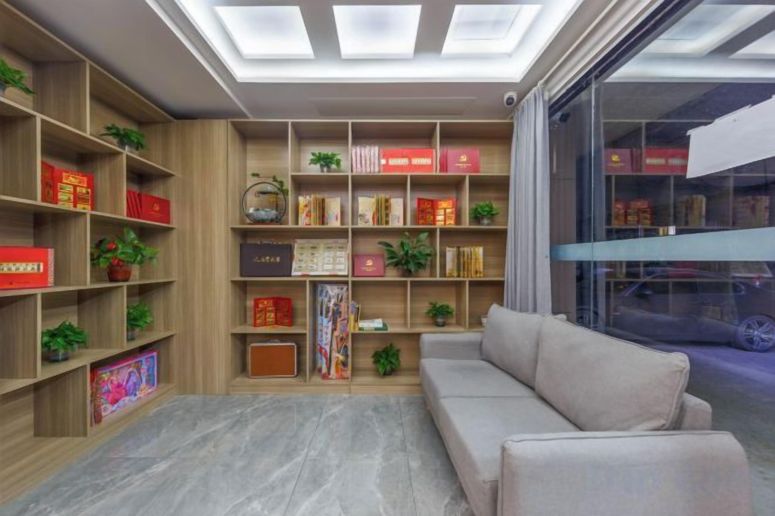 A modern living room with a sofa, wooden bookshelves, and a glass partition.