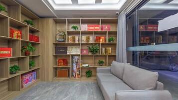 A modern living room with a sofa, wooden bookshelves, and a glass partition.
