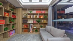 A modern living room with a sofa, wooden bookshelves, and a large window. - City Ant Hotel (Nanjing Wutang Square Metro Station) (Nanjing)