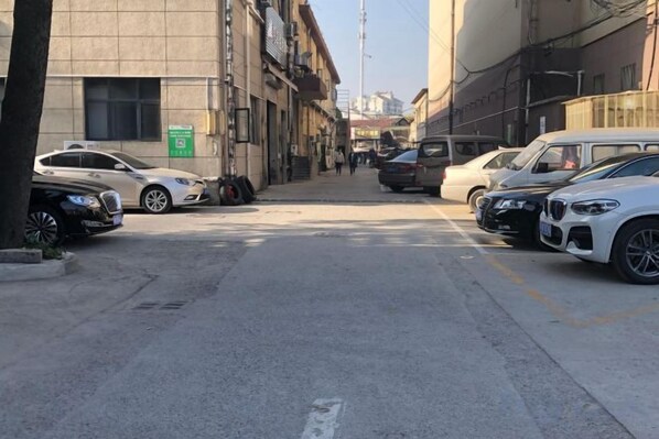 Una calle con autos estacionados y un edificio con un letrero verde.