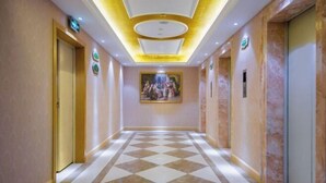 A hotel corridor with a checkered floor, a painting on the wall, and doors on both sides. - Vienna Hotel (Wuhan Central China Normal University, Huquan Metro Station) (Wuhan)