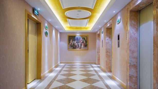 A hotel corridor with a checkered floor, a painting on the wall, and doors on both sides. - Vienna Hotel (Wuhan Central China Normal University, Huquan Metro Station) (Wuhan)